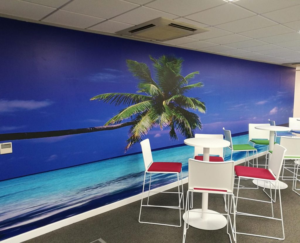Sandy beach scene with a palm tree installed on a wall of an office rest area.